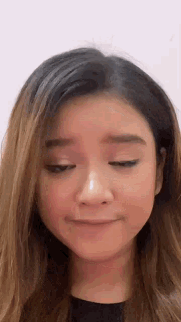 a woman is making a funny face with her eyes closed .