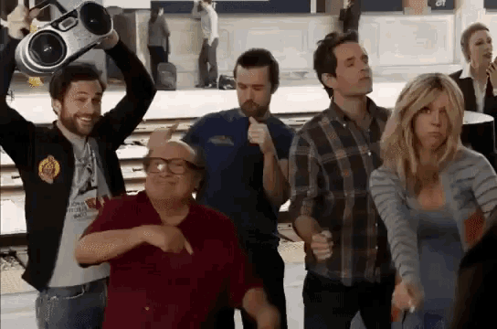 a group of people are dancing and one of them is holding a boombox over his head