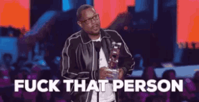 a man in a leather jacket is holding a trophy and giving a speech at a awards show .