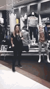 a woman is standing in front of mannequins in a store ..