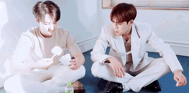 two men are sitting on the floor with their legs crossed