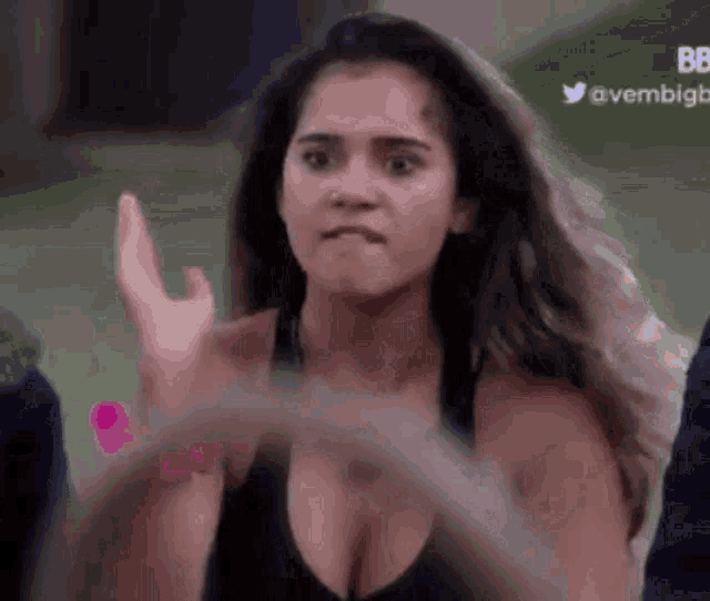 a woman in a black tank top is playing with a hula hoop .