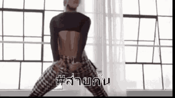a woman is dancing in front of a window in a room with a backless top .
