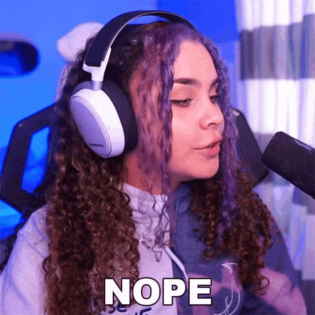 a girl with purple hair is wearing headphones and says nope in front of a microphone