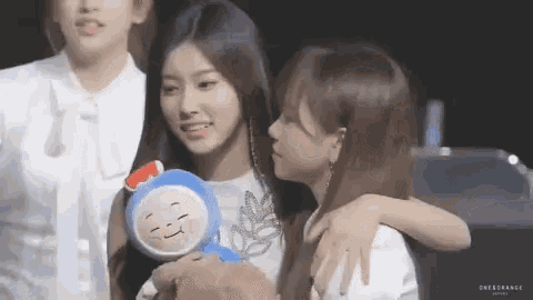 a group of young women are hugging each other and holding a stuffed animal .