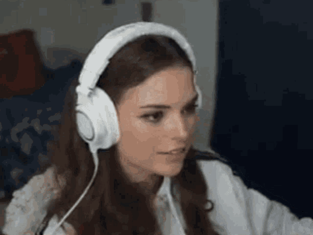 a woman is wearing headphones and looking at the camera .