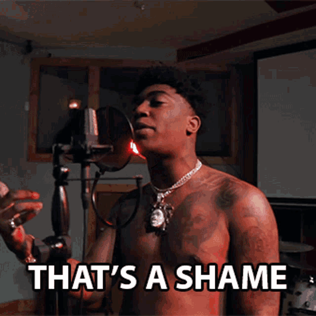 a shirtless man is singing into a microphone with the words that 's a shame written below him