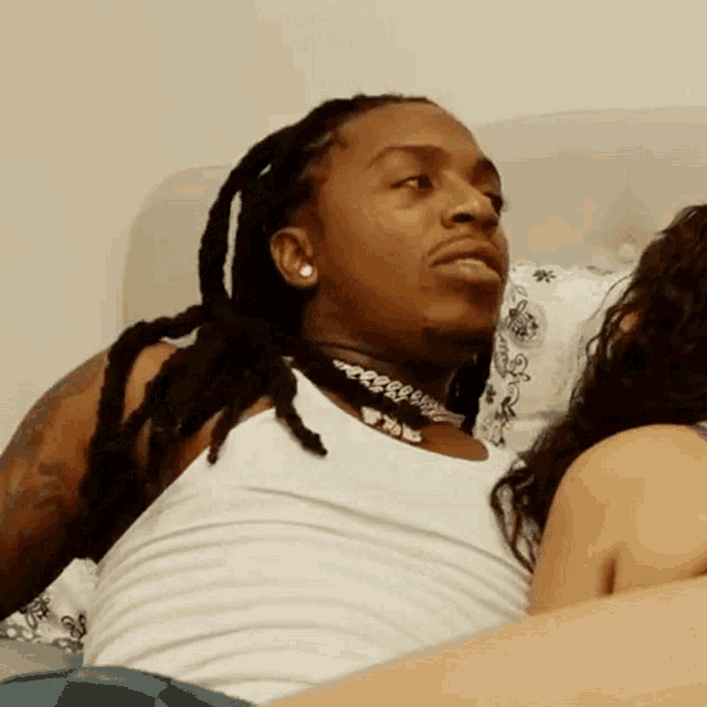a man with dreadlocks is laying next to a woman