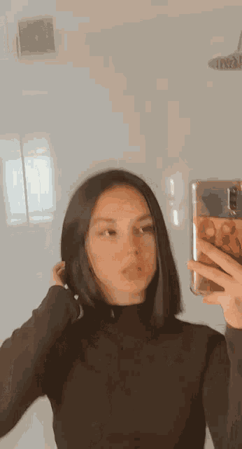 a woman is taking a selfie in a bathroom mirror with her phone .