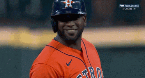 a baseball player wearing a helmet and an astros jersey smiles