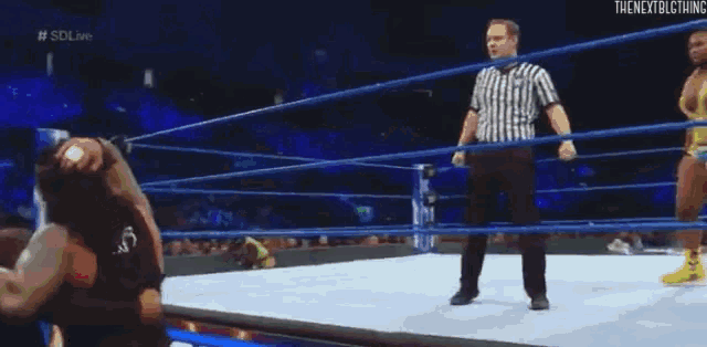 a wrestling match is being played in front of a crowd . one of the wrestlers is falling on the floor .