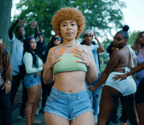 a woman in a green crop top and shorts is surrounded by people