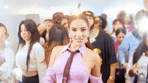 a woman in a purple shirt and tie is surrounded by people