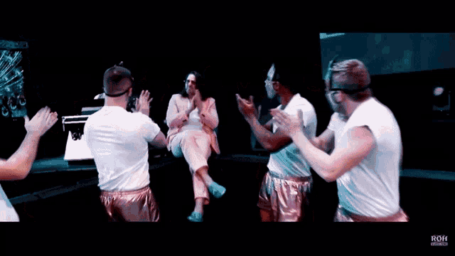 a group of people are clapping in front of a screen that says roh on it
