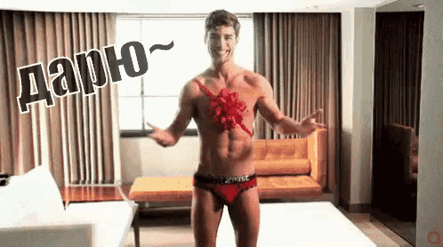 a shirtless man in red underwear is standing in a living room with a couch and curtains