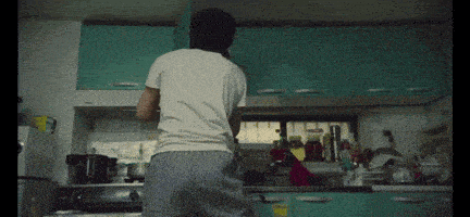a man in a white shirt is standing in a kitchen talking on a cell phone