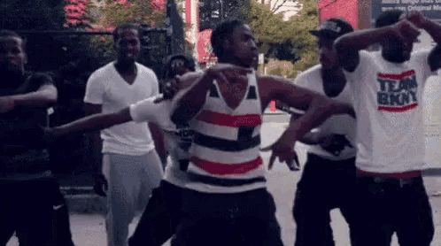 a group of young men are dancing and one of them is wearing a shirt that says team brooklyn