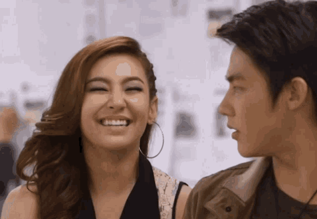 a woman wearing hoop earrings smiles next to a man