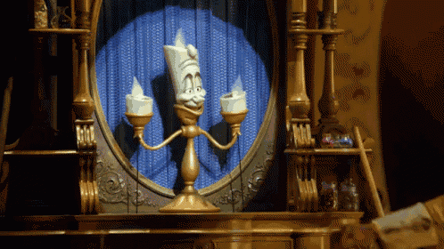 a statue of a candle holder with a face on it is in front of a mirror