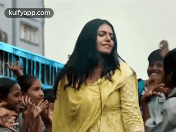 a woman in a yellow shirt is dancing in front of a crowd of people .