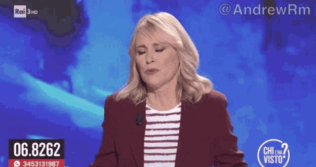 a woman in a red jacket stands in front of a blue background with 06.8262 on it