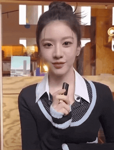 a woman in a black and white sweater is holding a black object