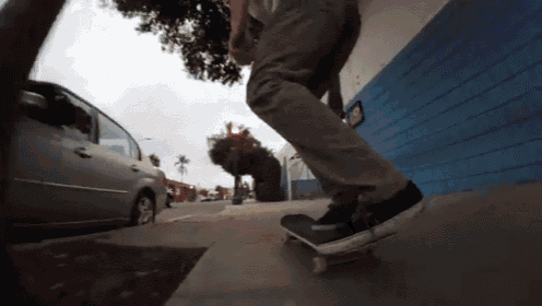 a man is riding a skateboard down a sidewalk in front of a blue wall