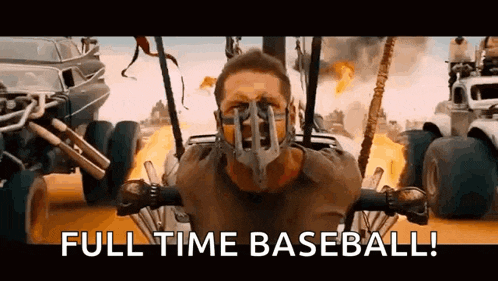 a man wearing a mask is sitting in a buggy with the words `` full time baseball '' written above him .