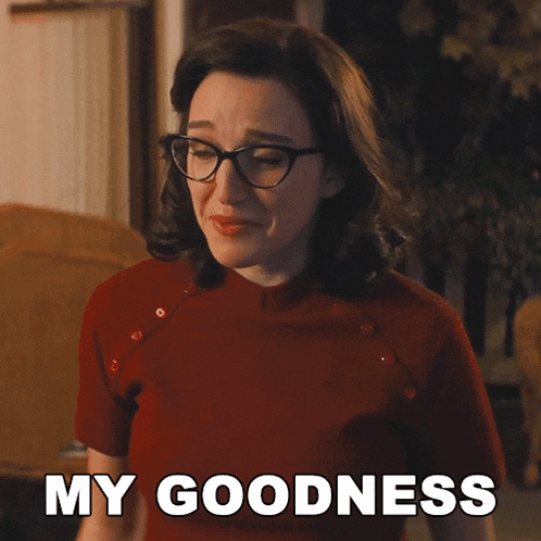 a woman wearing glasses and a red shirt is smiling and says my goodness
