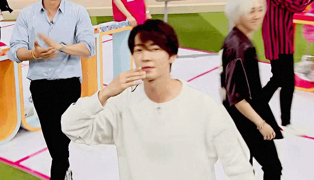 a man in a white sweater is dancing on a stage with other people