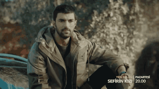 a man with a beard is sitting in front of a sign that says sefirin kizi 20.00