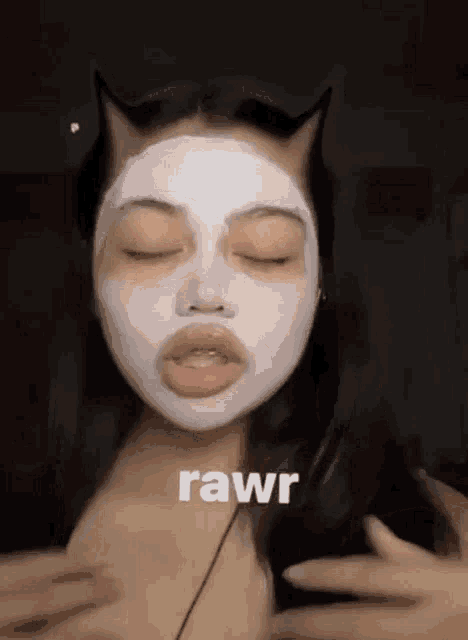 a woman is wearing a white mask on her face and has cat ears .