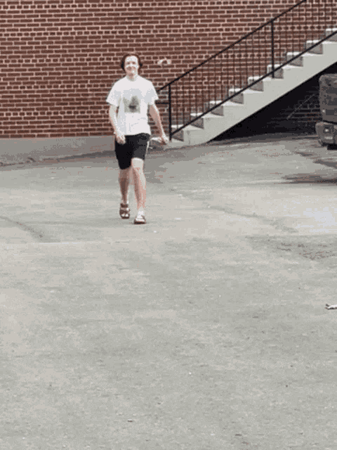 a person walking in front of a brick building with stairs behind them