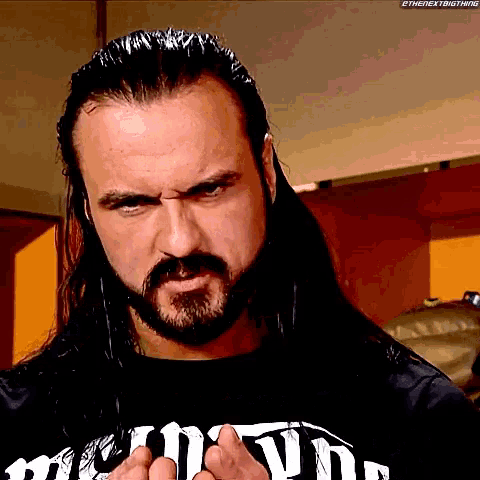 a man with long hair and a beard is wearing a t-shirt that says ' the next big thing '