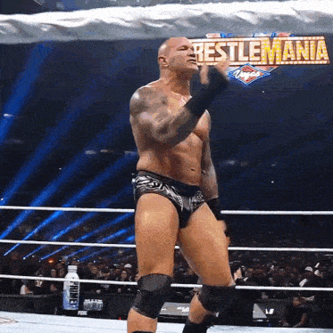 a man in a wrestling ring with a sign that says wrestlemania on it