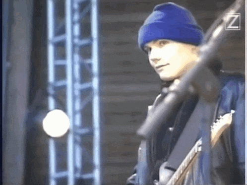 a man in a blue hat is playing a guitar on stage .