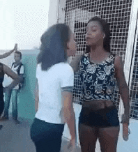 two women are standing next to each other in front of a fence .