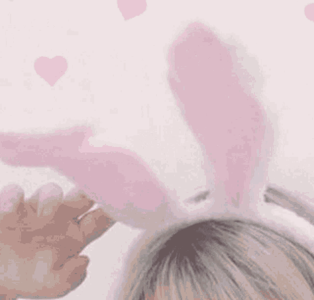a close up of a person wearing a headband with pink bunny ears on their head .