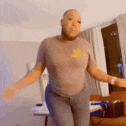 a man is dancing in a living room while wearing a t-shirt with a yellow logo on it .