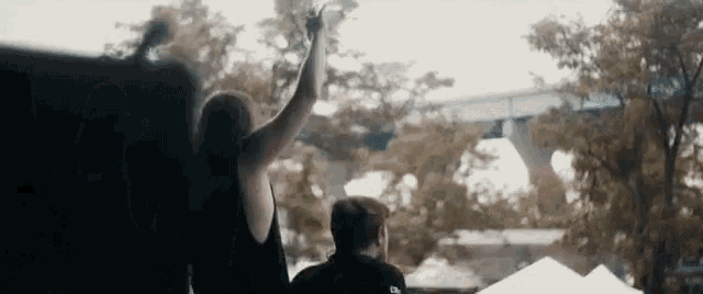 a man and a woman are standing next to each other with their hands in the air .