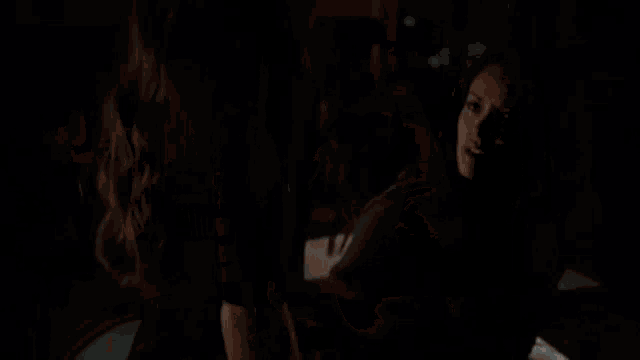 a woman is kneeling on a bed in a dark bedroom