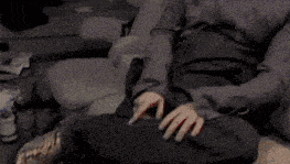 a person is sitting on a couch with their hands on their thighs