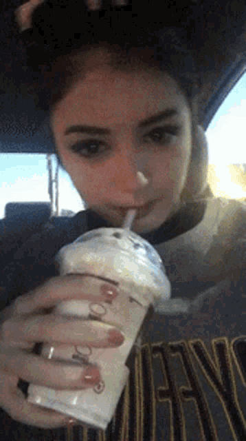a girl in a nirvana shirt drinks a milkshake through a straw