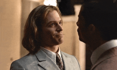 two men are looking at each other and one is wearing a suit