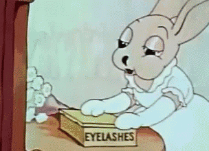 a cartoon rabbit is looking at a box of eyelashes on a table