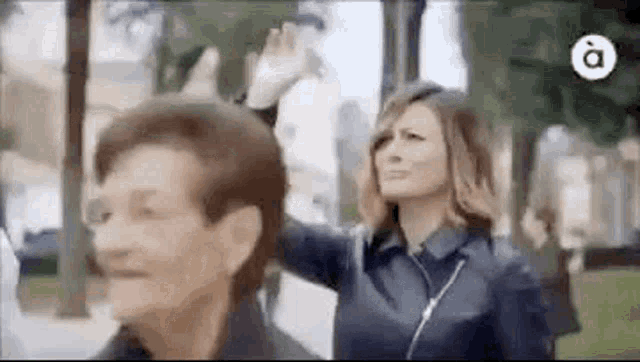a woman is standing next to an older woman waving her hand .