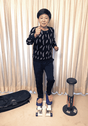 a woman in a black sweater stands on a stepper