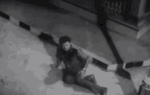a black and white photo of a man kneeling on the ground .