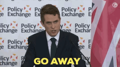 a man in a suit and tie is standing at a podium giving a speech and says `` go away '' .