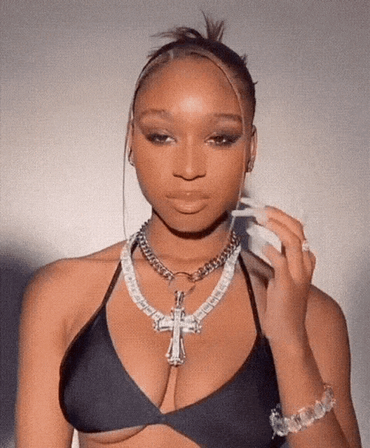 a woman in a black bikini top is wearing a necklace with a cross on it .